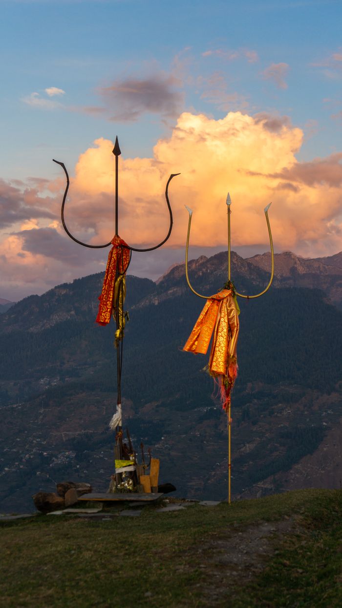 Services Vibrant sunset behind sacred tridents in Bijli Mahadev, Himachal Pradesh.