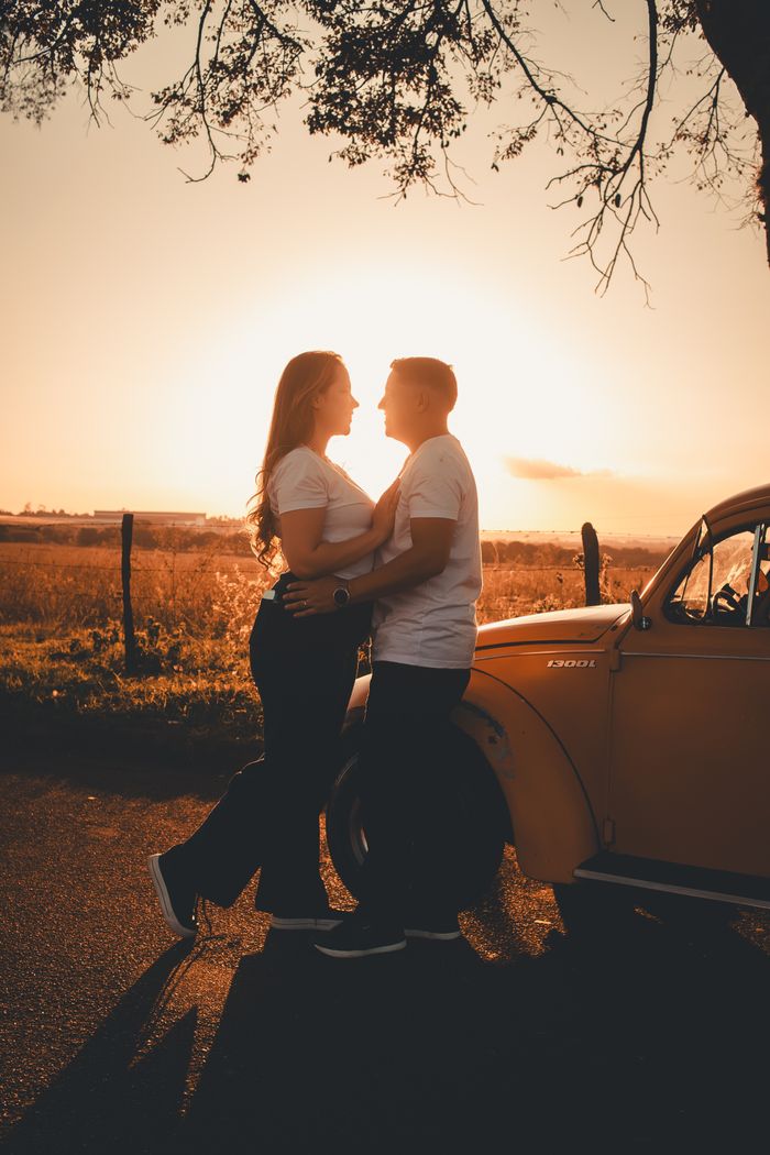 Mastering the First Impression: Your intriguing post title goes here A couple embraces next to a vintage car during a beautiful sunset.